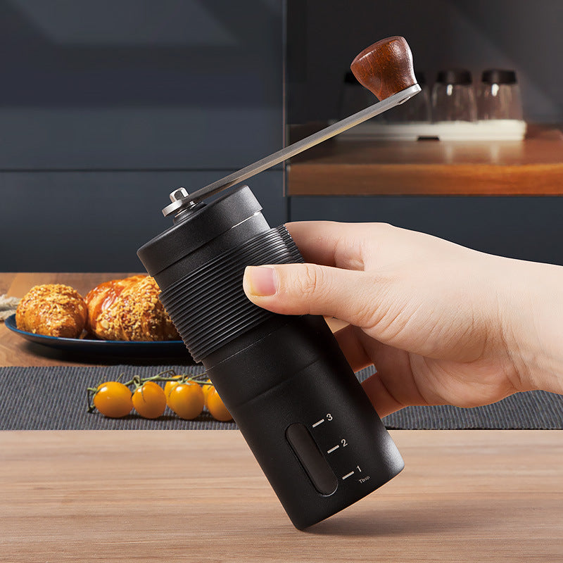 Hands turning the crank of the black manual grinder included in the kit