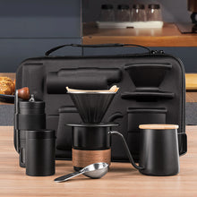 Black hand grinder, metal dripper, pouring kettle and cup arranged in front of the kit case