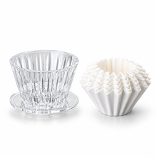 Clear PC pour-over dripper with 50 white paper filters on a white background